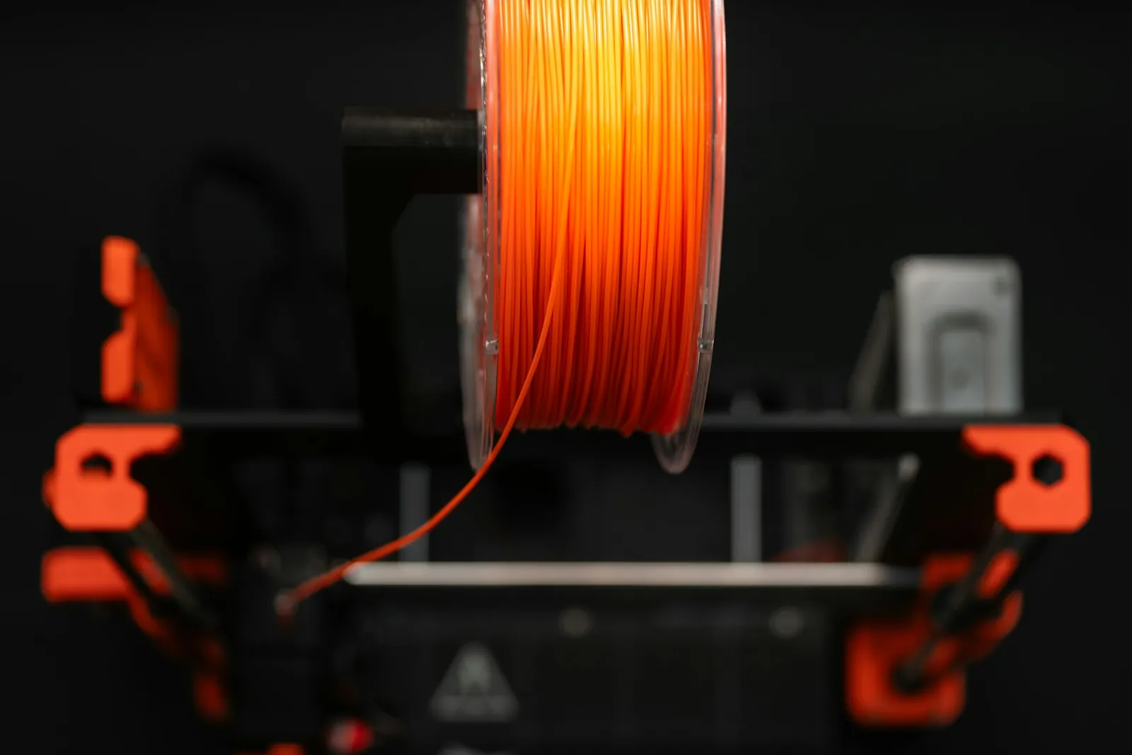 Carretel de filamento laranja montado na impressora 3D