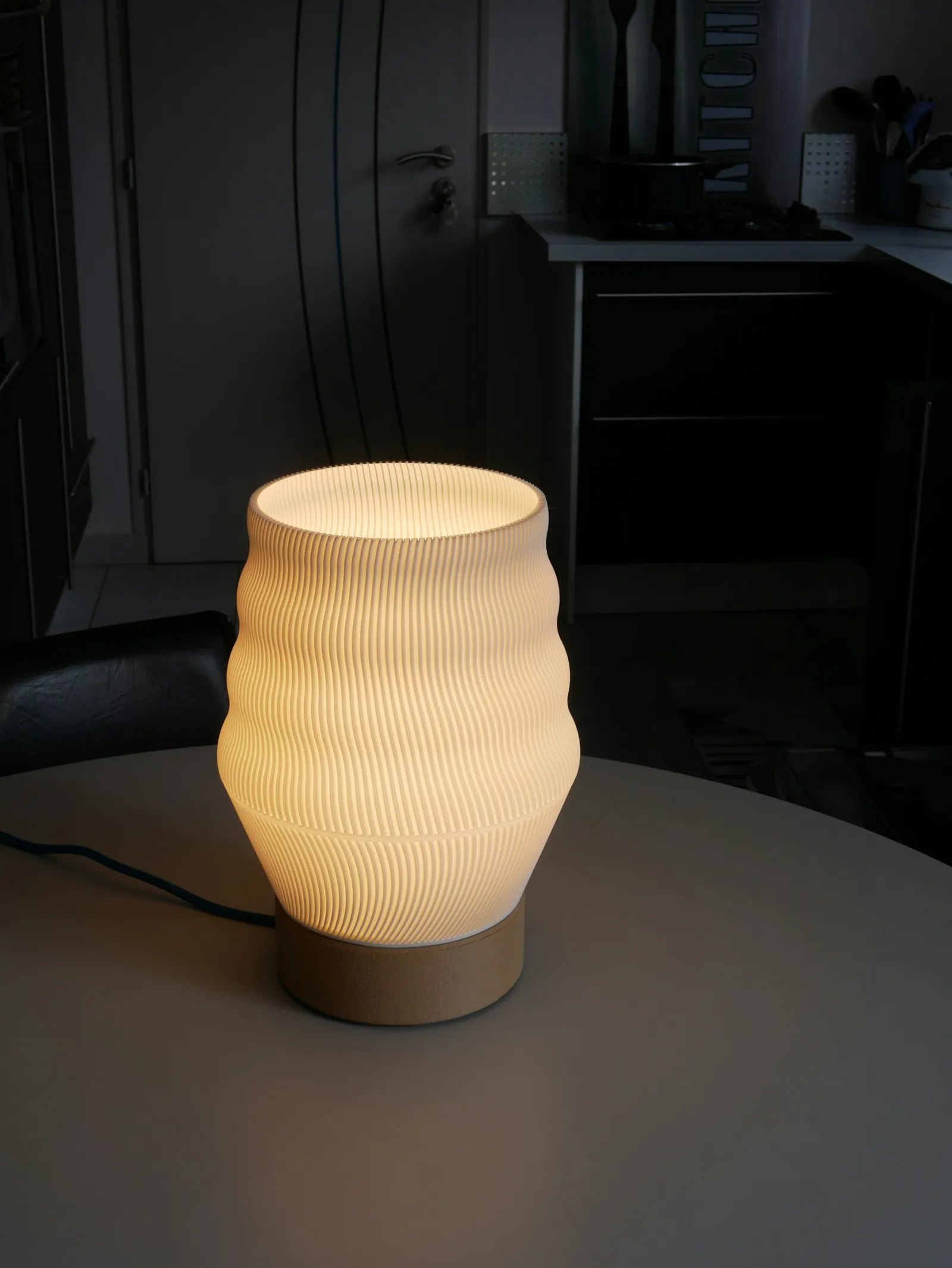 Luminária branca impressa em 3D, acesa sobre uma mesa