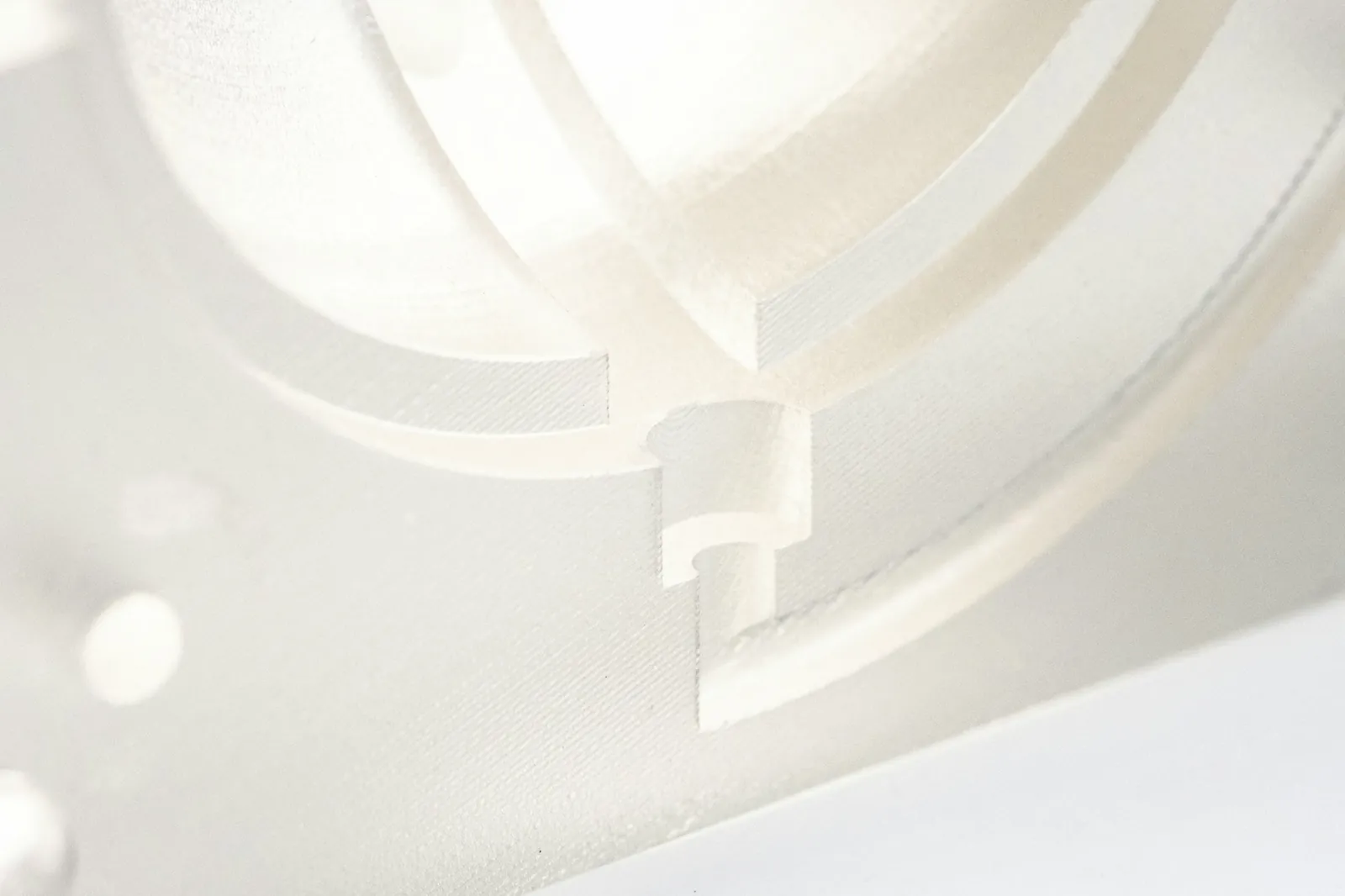 Detalhe de uma peça técnica branca impressa em 3D, com canais e encaixes