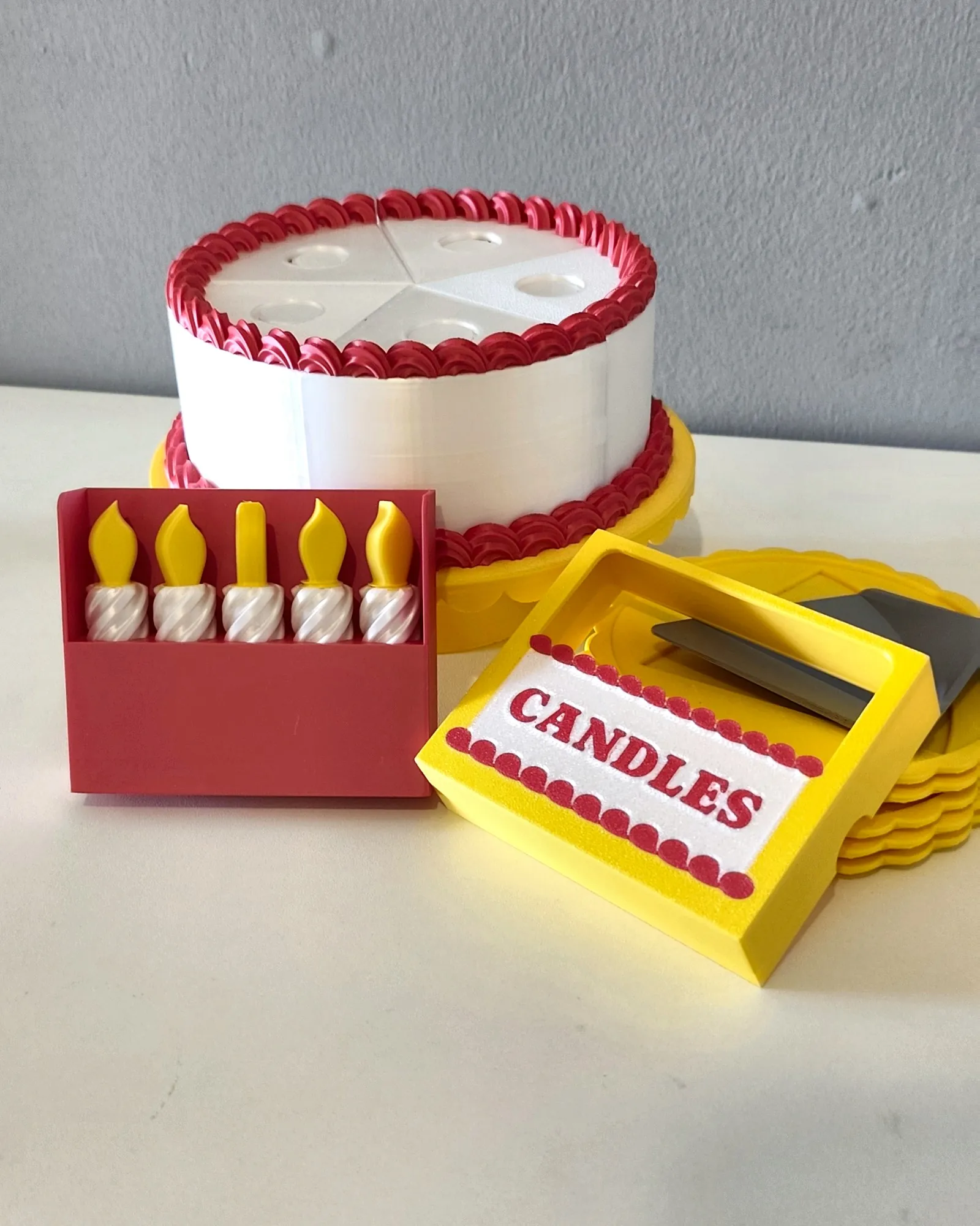 Caixa de velas amarela na frente do bolo impresso em 3D pela Dédalo