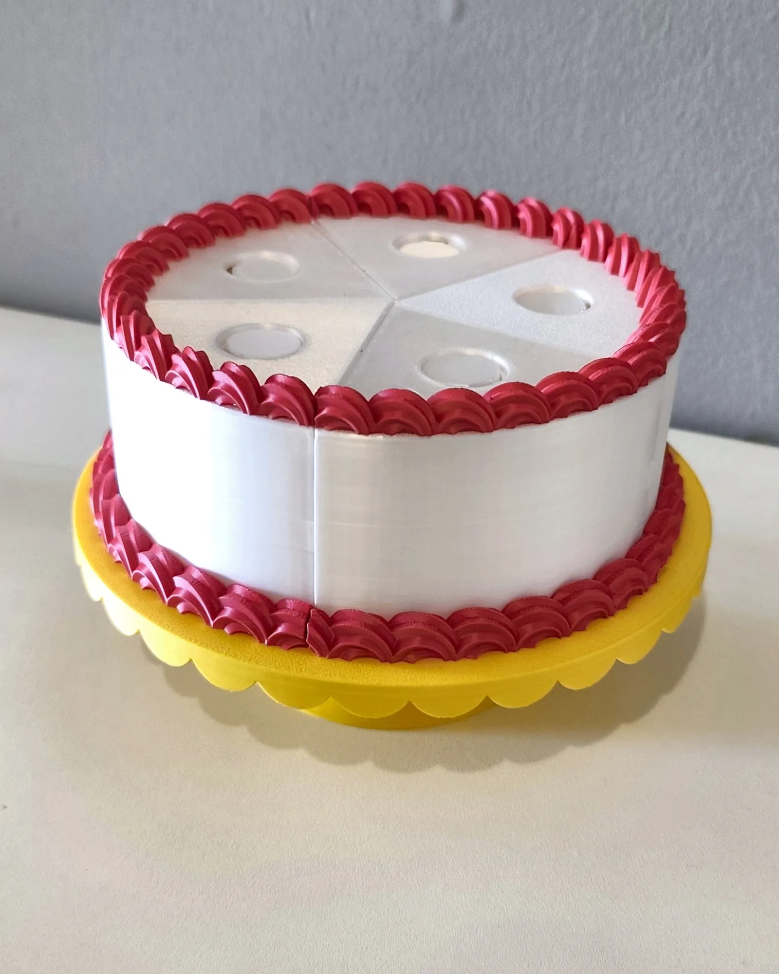 Bolo inteiro com cobertura vermelha no suporte amarelo, impresso em 3D pela Dédalo