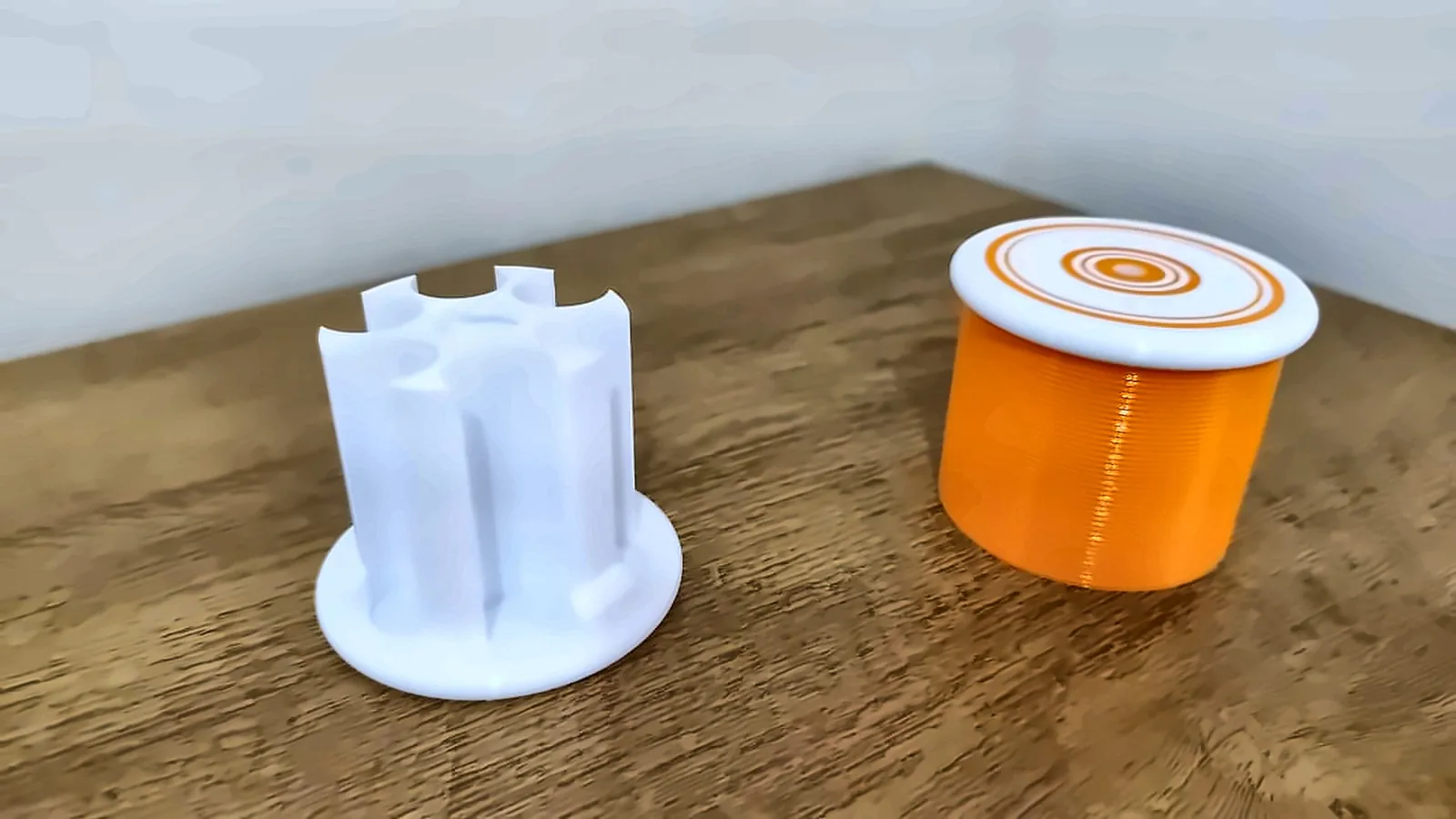 Pote laranja com tampa e suporte branco, impressos em 3D pela Dédalo