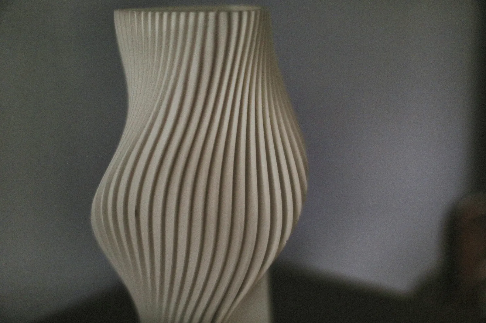 Vaso branco torcido impresso em 3D, com as linhas de camada aparentes
